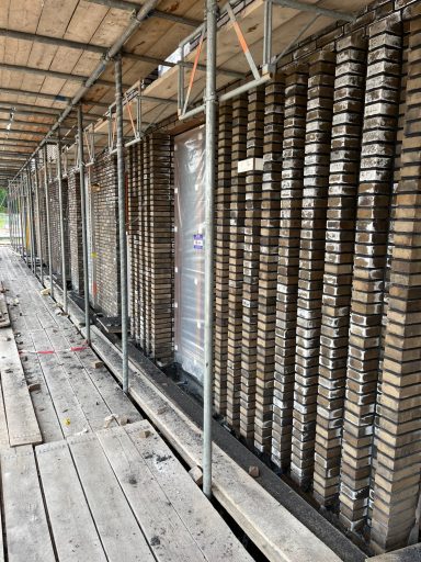 Stapels gevelstenen op een steiger, met zichtbare structuur en horizontale rijen.